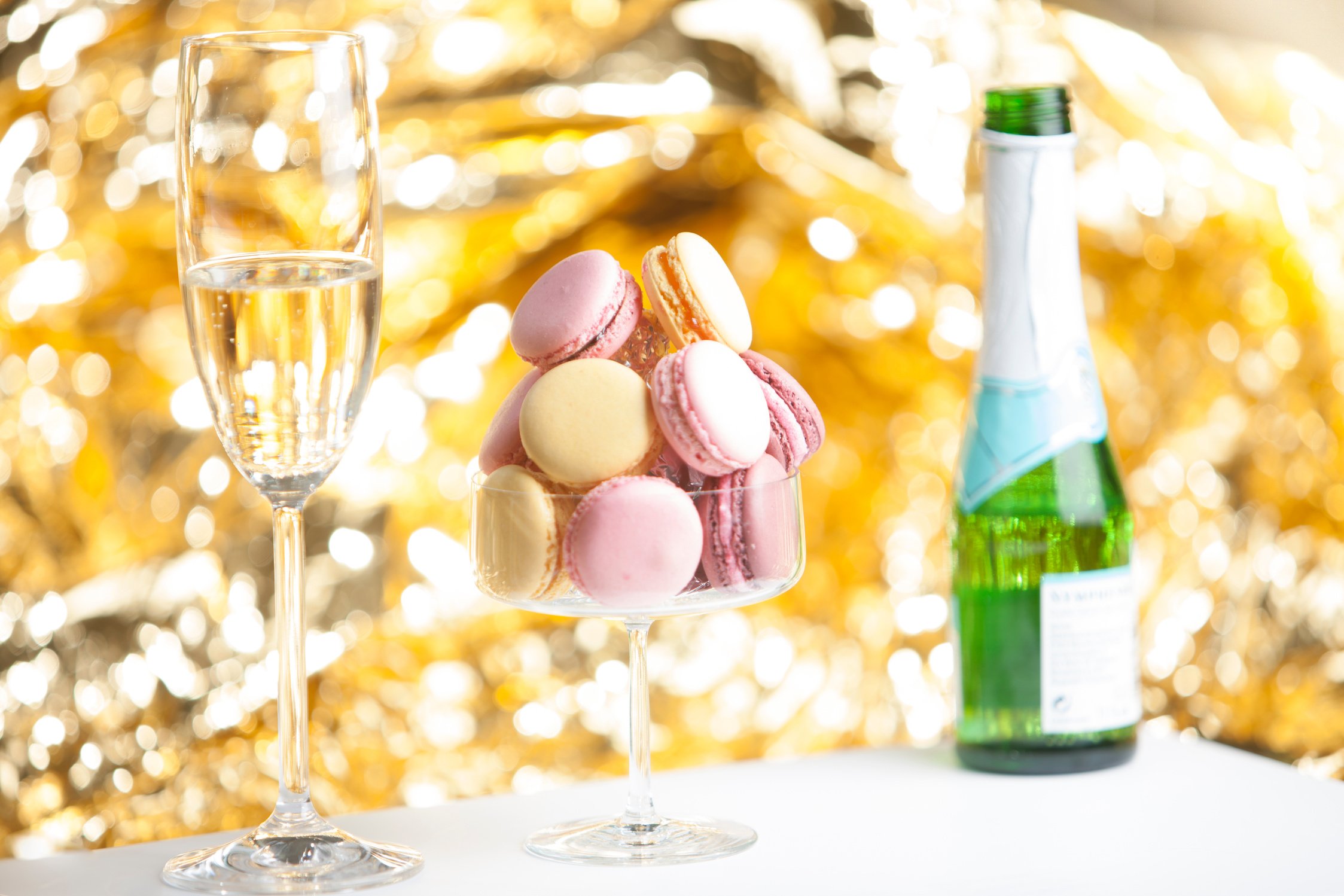 Macarons in glass with a glass of champain, golden background